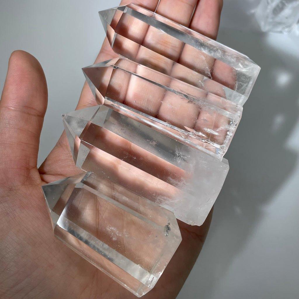 Hand holding multiple clear quartz towers for size comparison